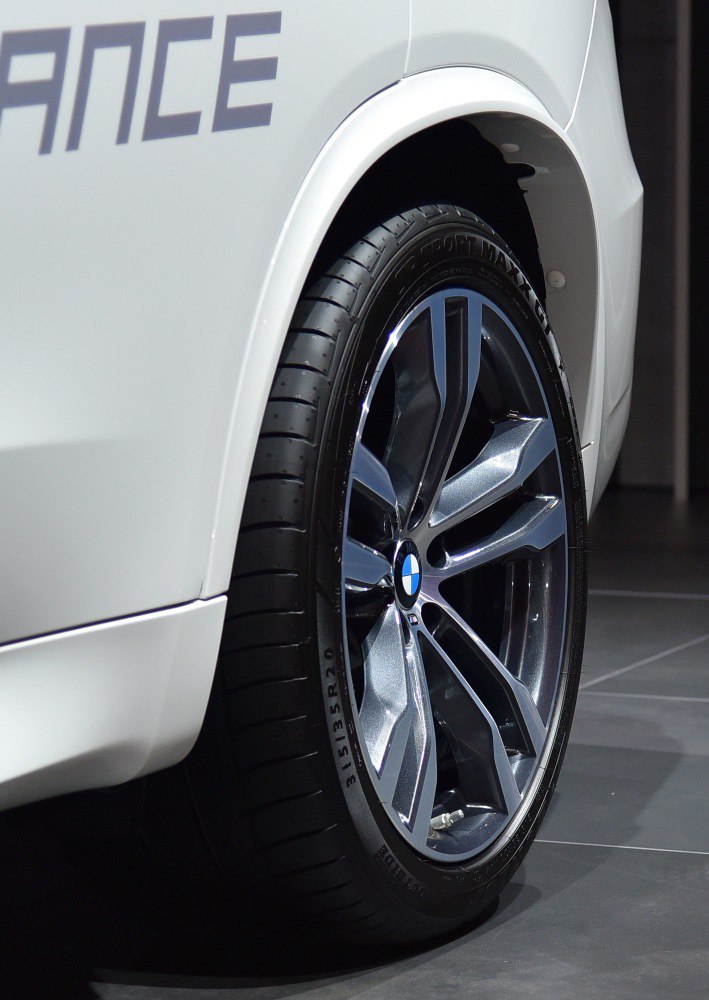Detailed close-up of an alloy wheel and tire on a white luxury SUV.
