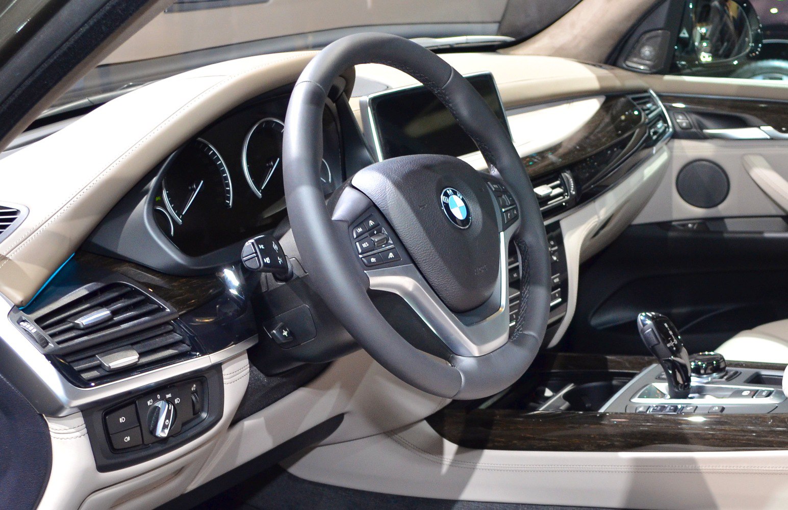 Modern steering wheel and dashboard with beige interior and wood accents
