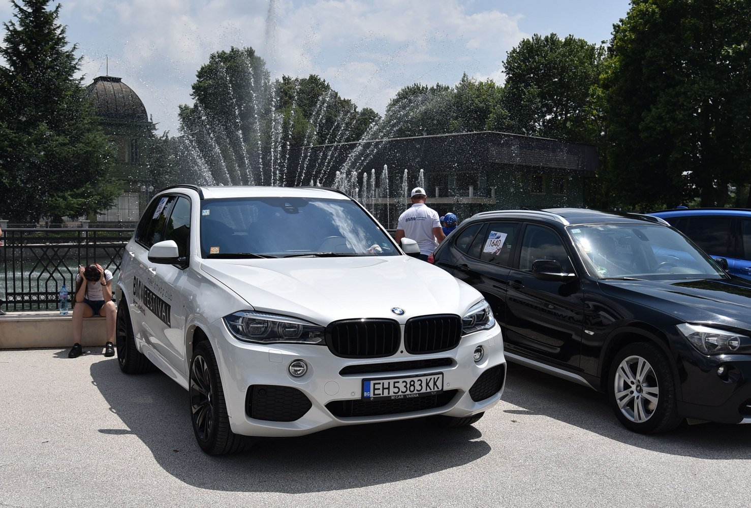 Front view of white BMW SUV with fountain background