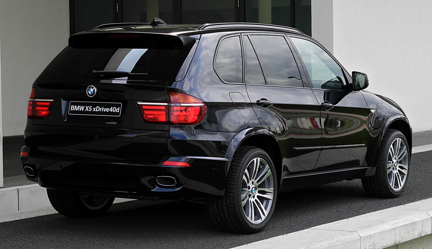 Rear three-quarter view with dual exhausts, alloy wheels, tinted windows