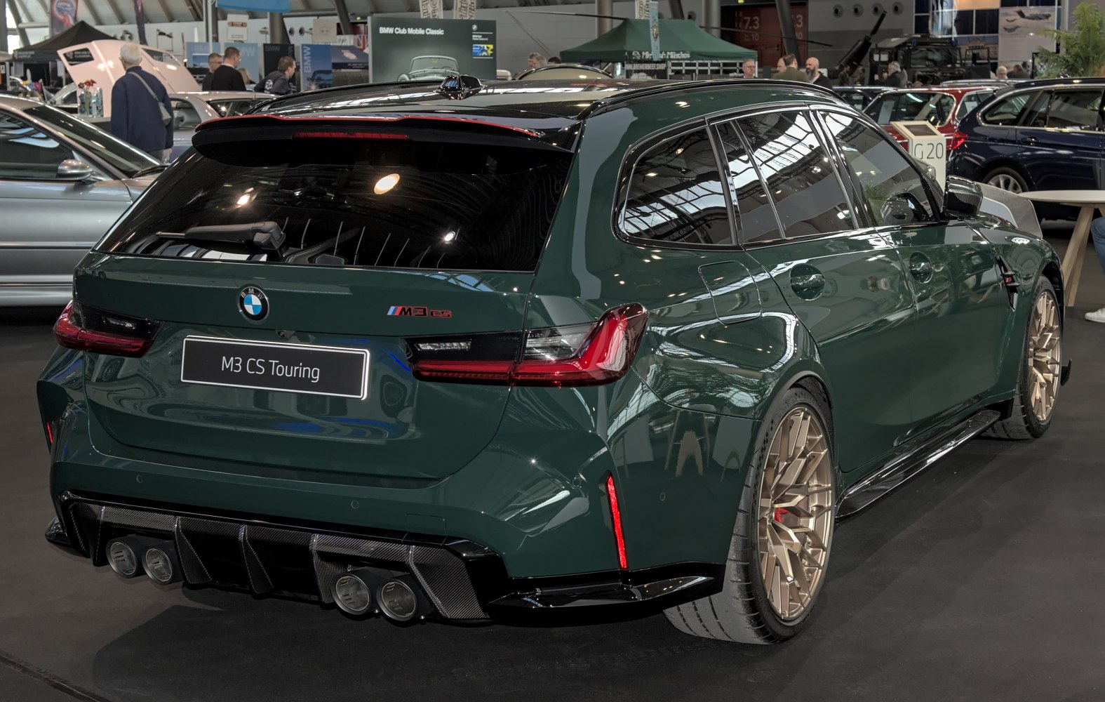 Rear view of a green wagon with quad exhaust and bronze multi-spoke wheels
