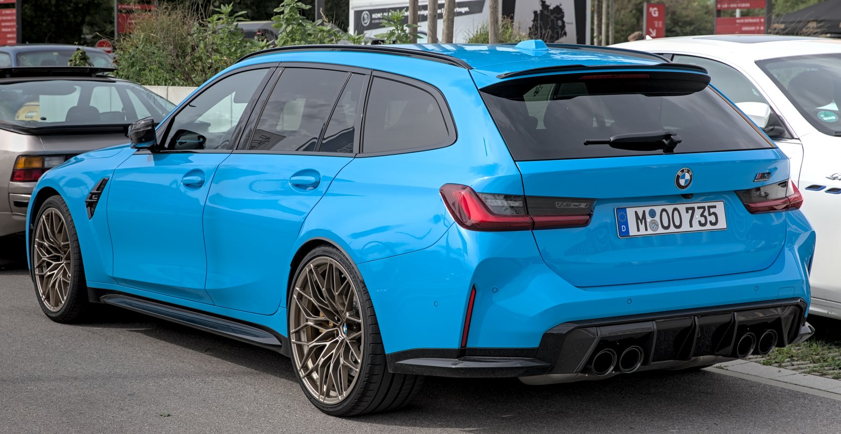 Bright blue sporty touring car rear and side with quad exhaust.