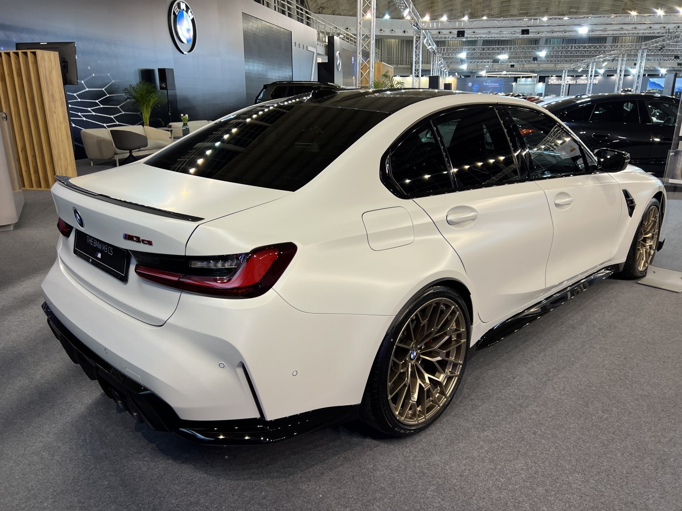 White high-performance sedan with gold multi-spoke wheels and sporty rear