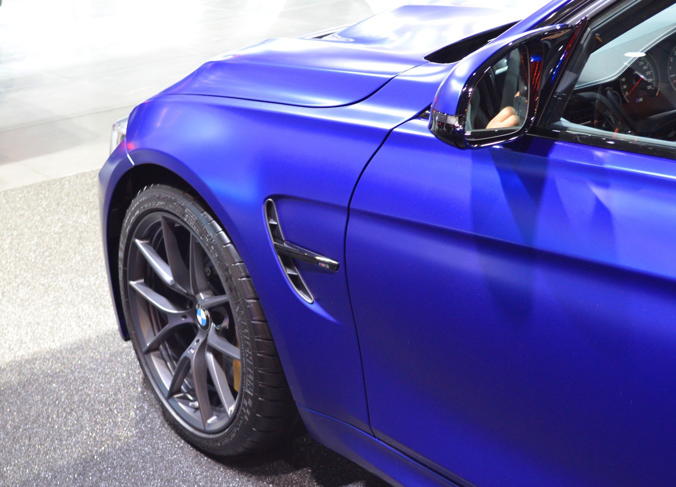 Close-up of front fender vent and alloy wheel in matte blue finish