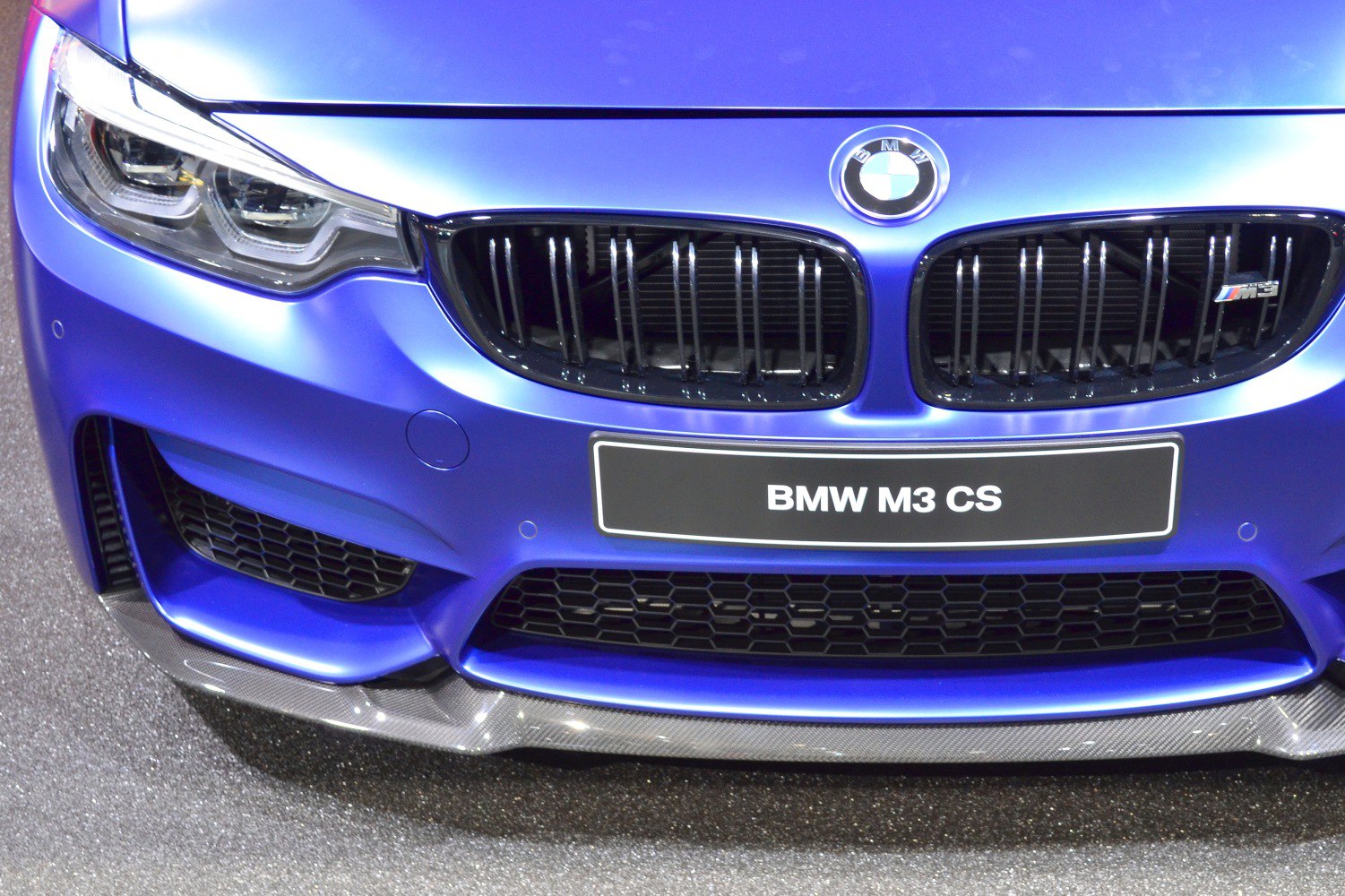 Close-up of blue front grille and sharp headlight design.