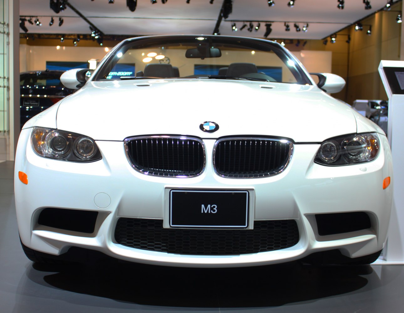 Front view featuring kidney grille and headlights of a white convertible sports car