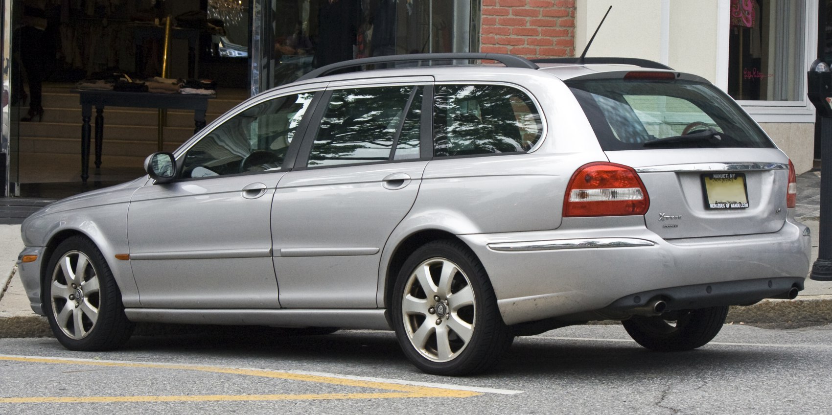 Silver estate wagon with alloy wheels and roof rails rear side view