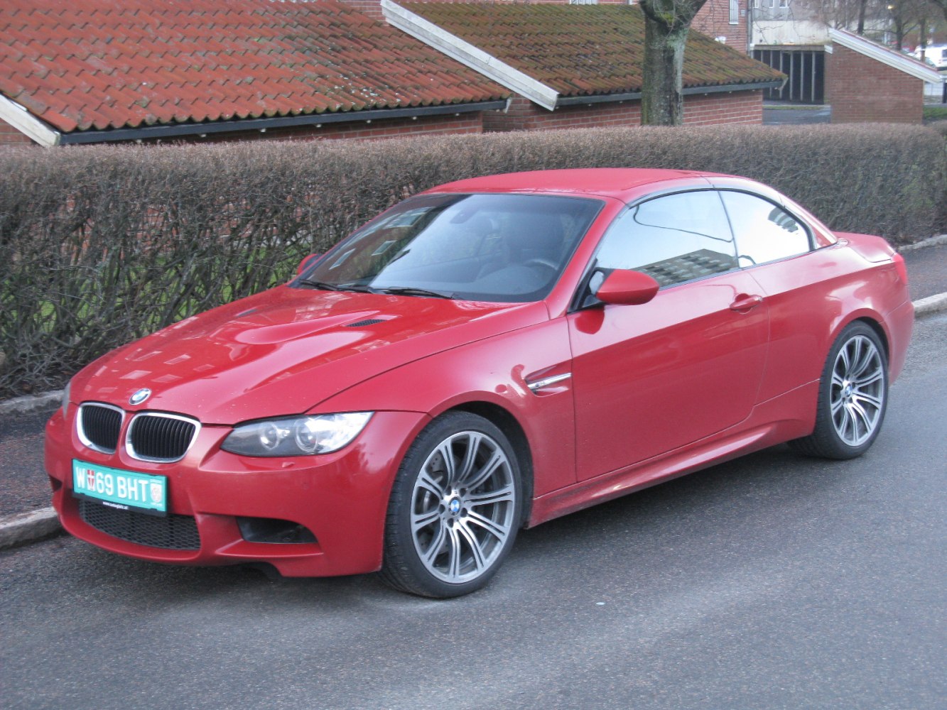 Red sporty coupe front side with alloy wheels and headlights