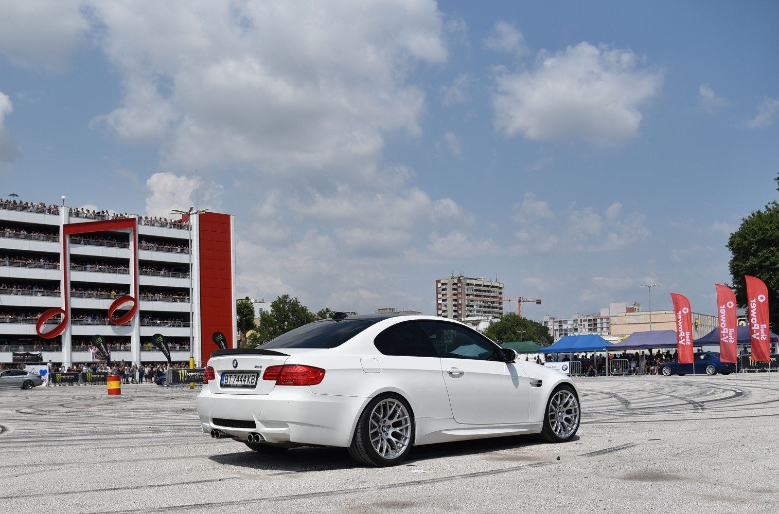 Rear and side view of white coupe with sporty wheels and quad exhaust