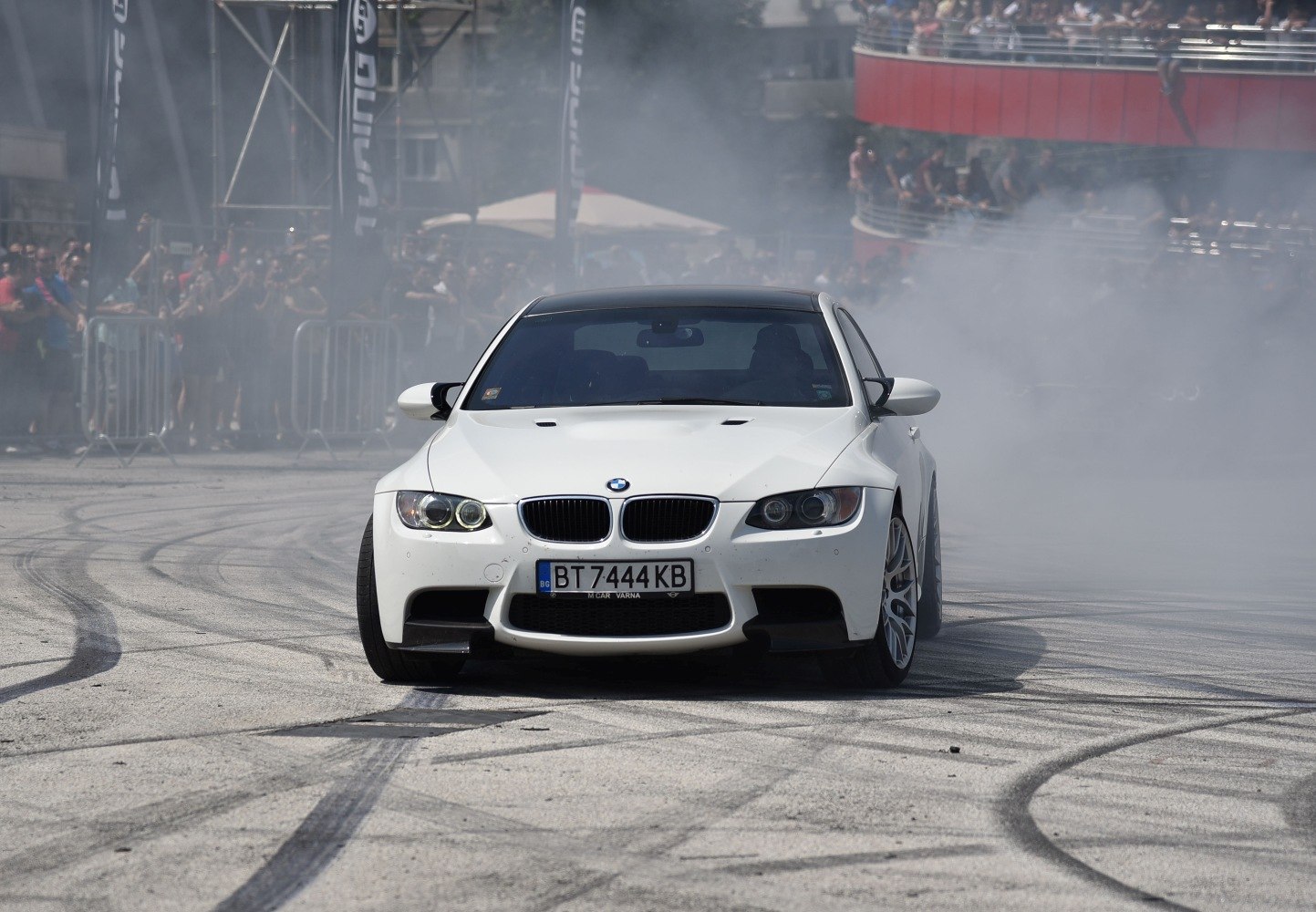 Front view of a drifting sports coupe with smoke and tire marks