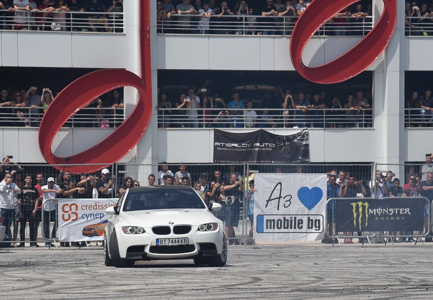 White sporty coupe drifting at car event with crowd watching closely