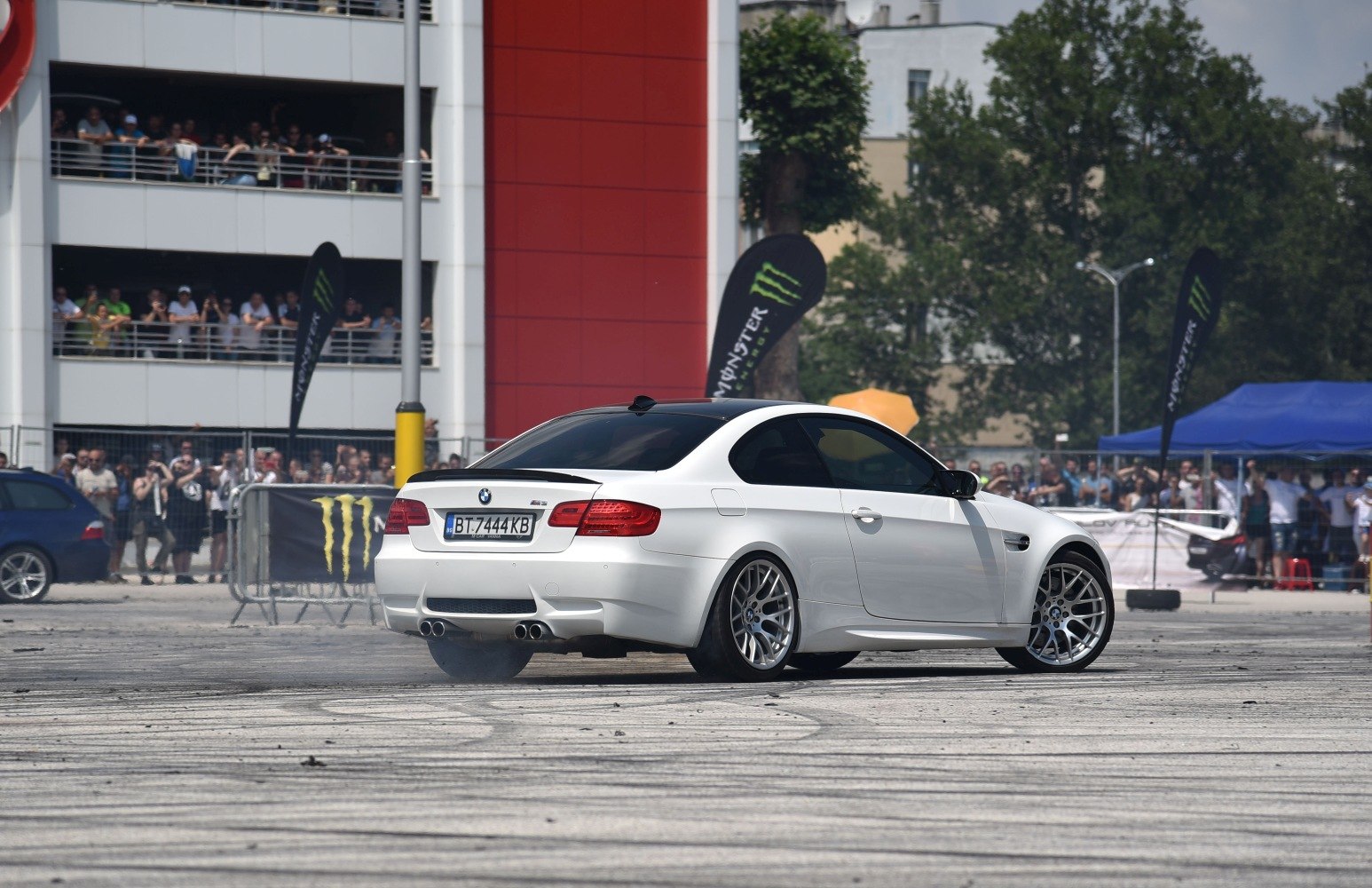White coupe drifting with aftermarket wheels and rear spoiler