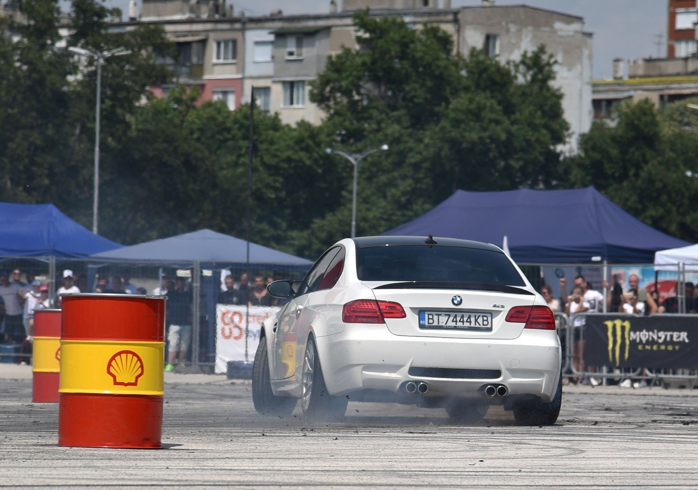 Rear view of a vehicle drifting with tire smoke on asphalt near racing barrels