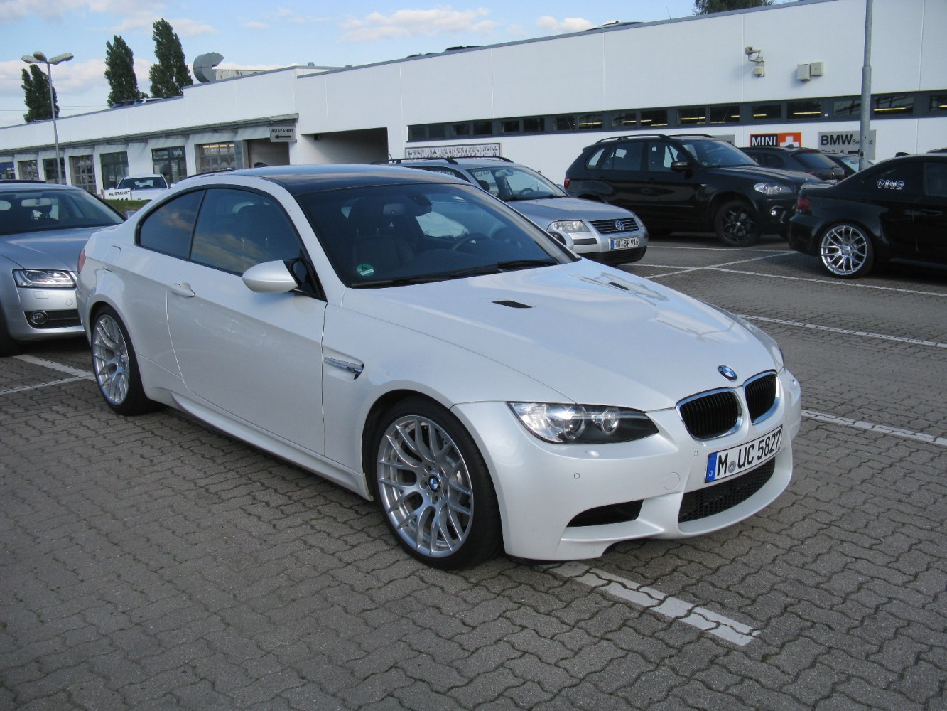 White coupe with sporty front and alloy wheels parked in lot
