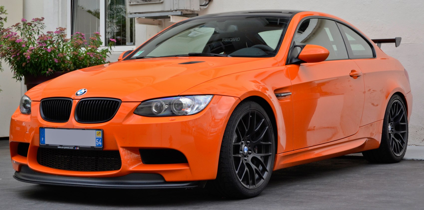 Orange coupe with black alloy wheels and rear spoiler