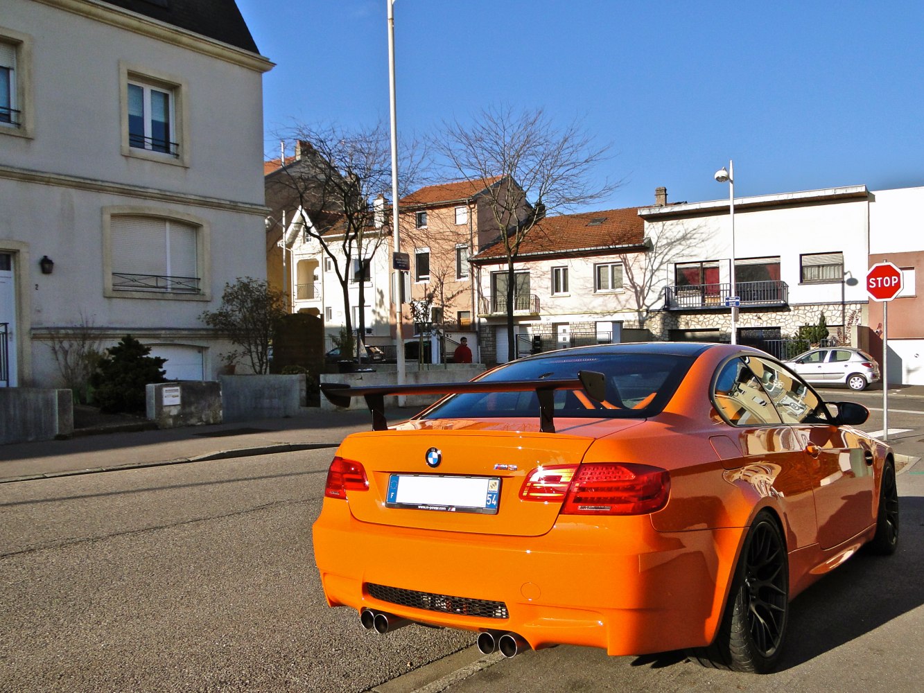 Rear view of orange sports coupe with large rear wing and quad exhausts