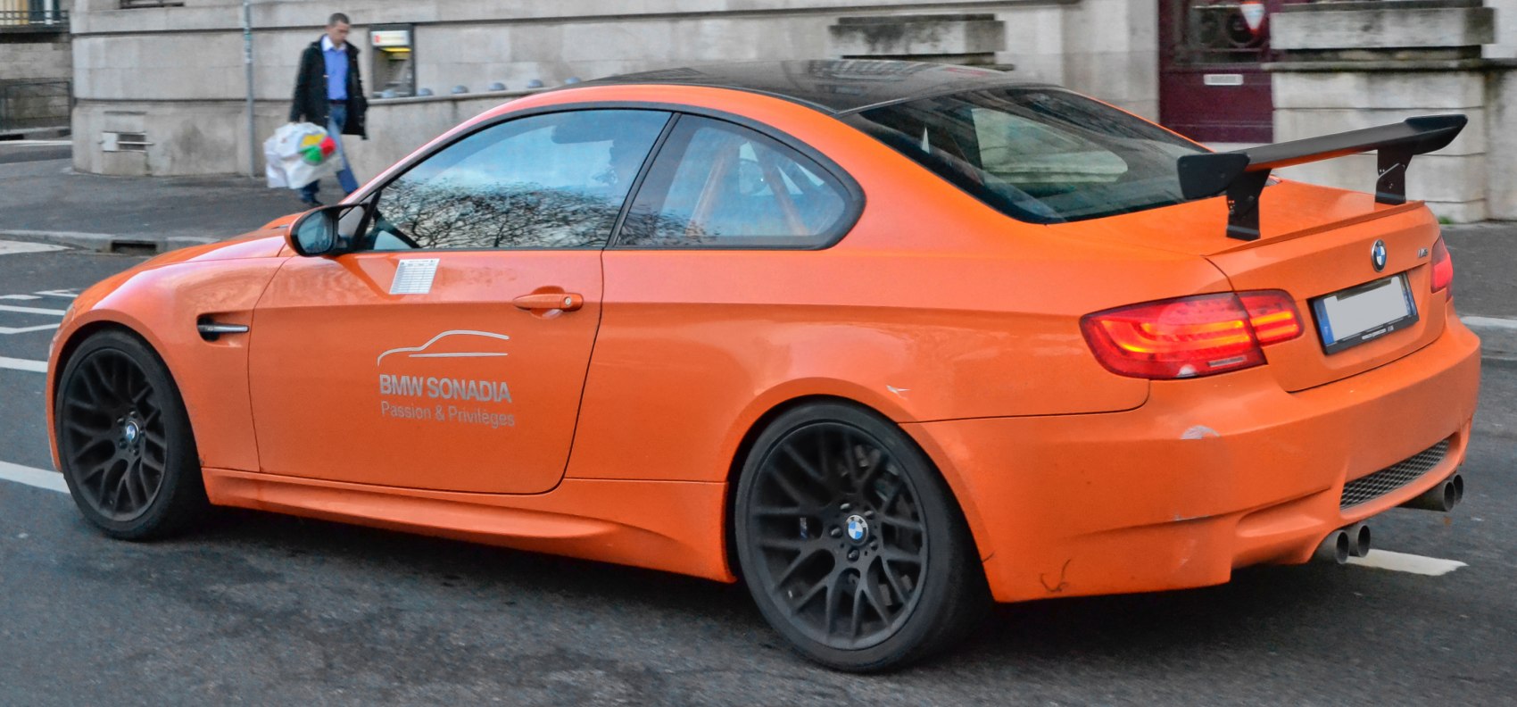Bright orange coupe with large rear wing and black multi-spoke wheels