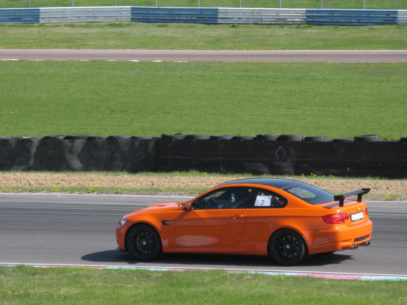 Orange coupe with black rear wing on a racetrack