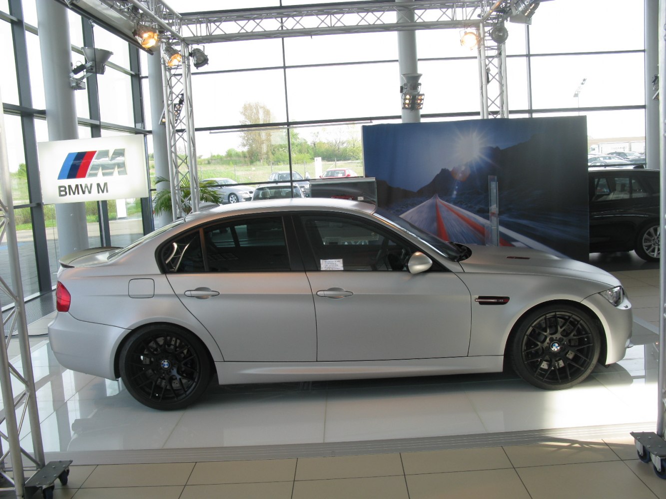 Silver sedan with black multi-spoke wheels in showroom