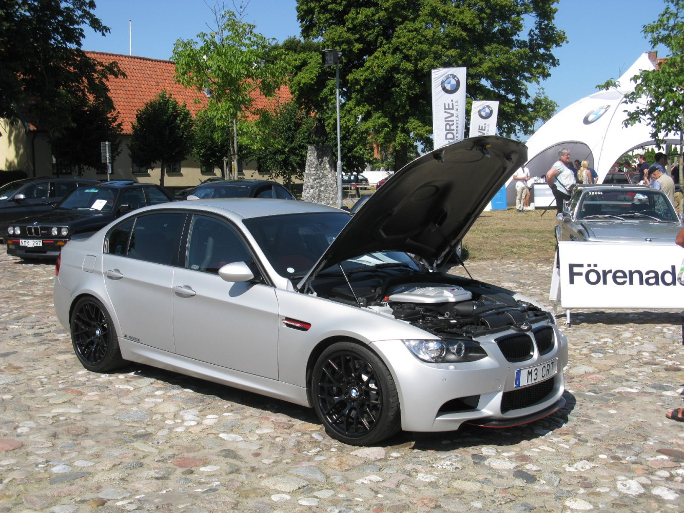 Silver sedan with open hood and black multi-spoke wheels