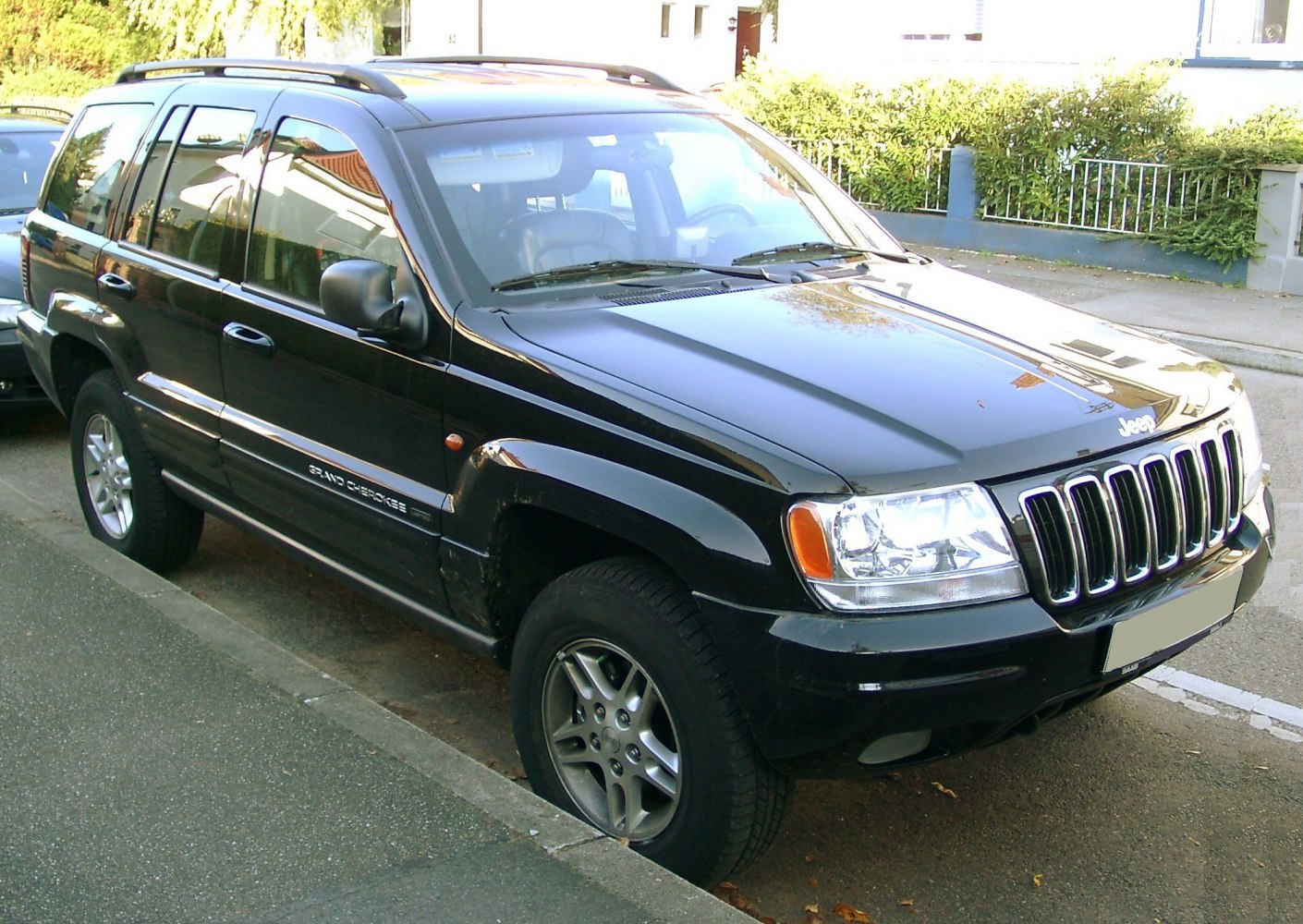 Front-side view of black mid-size SUV with seven-slot grille and roof rails