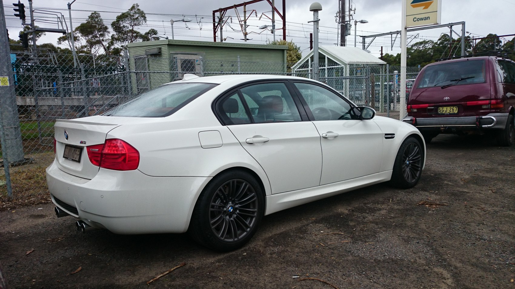 White sedan with black multi-spoke wheels and quad exhaust