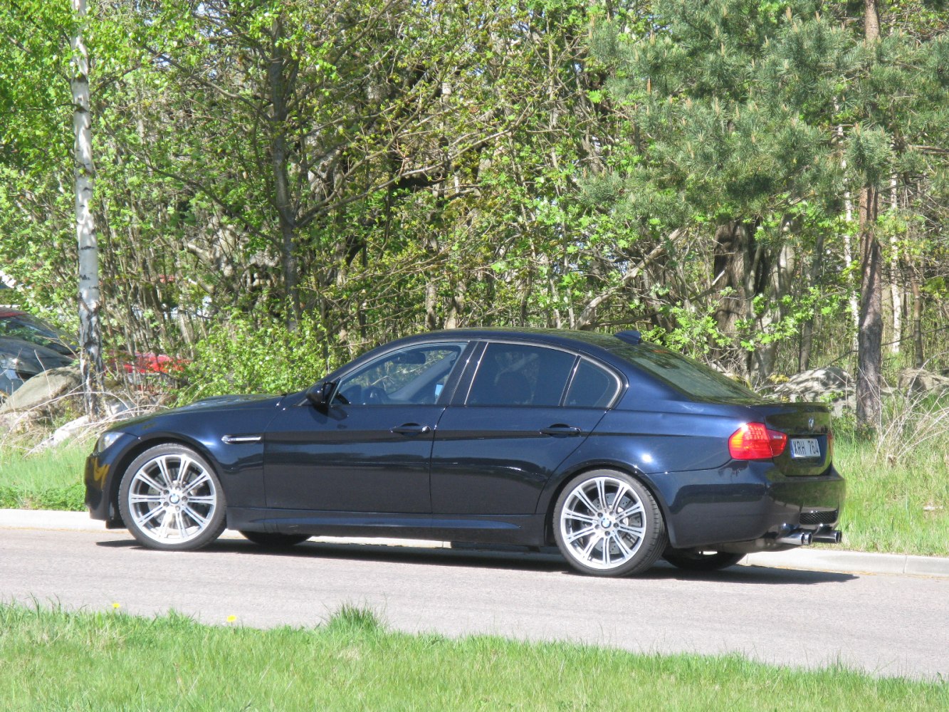 Dark blue sedan side view with alloy wheels and sporty design