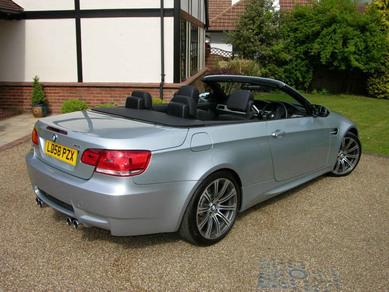 Rear view of a silver convertible with open soft top and quad exhausts