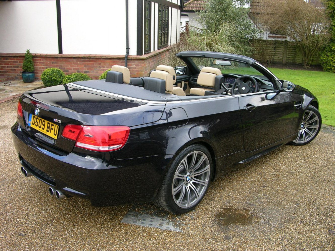 Rear view of convertible showing quad exhausts and beige leather interior