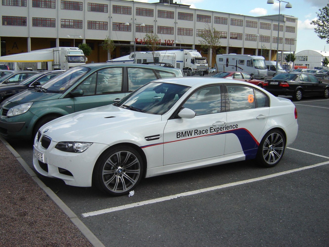 White sedan with BMW Race Experience branding parked in lot
