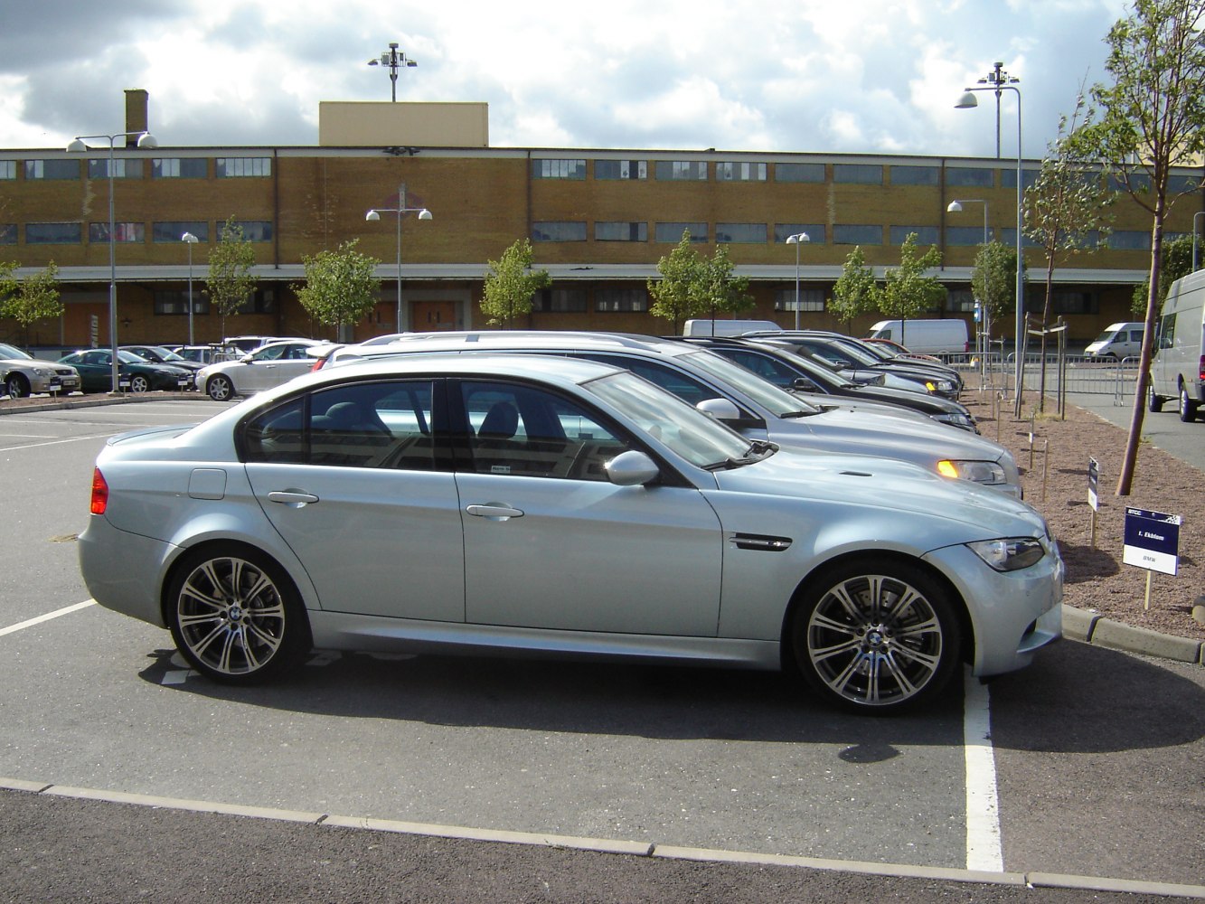 Silver four-door sedan side profile with alloy wheels in parking lot