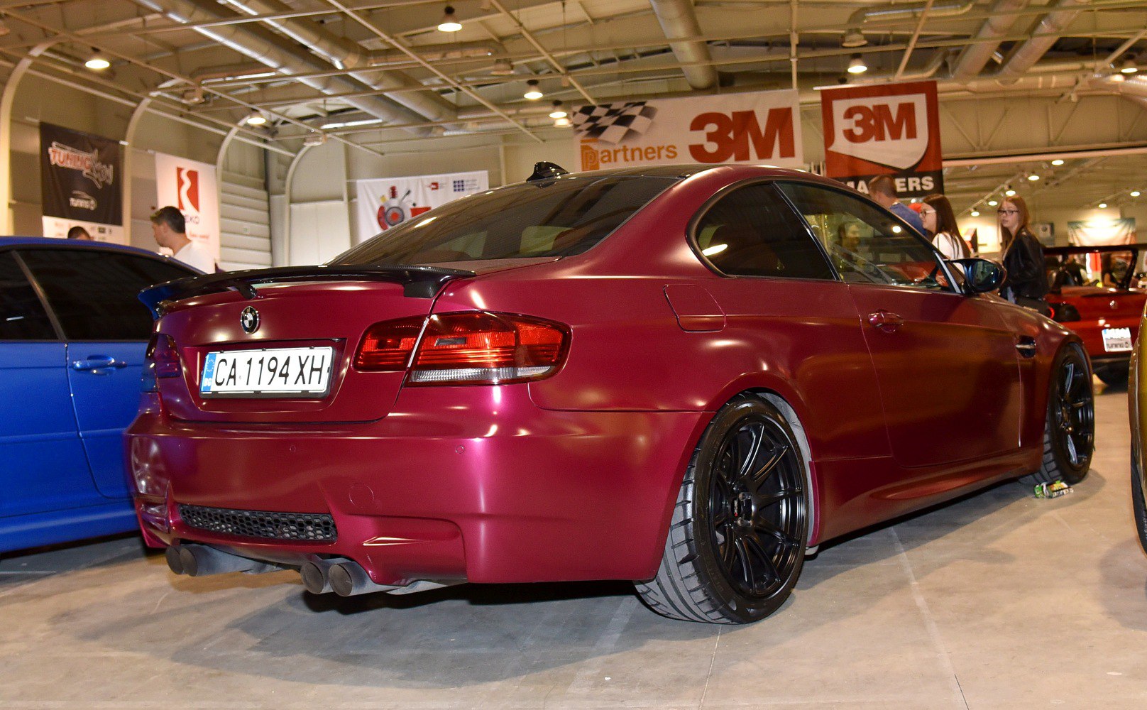 Red coupe rear view with spoiler, dual exhaust, and black rims