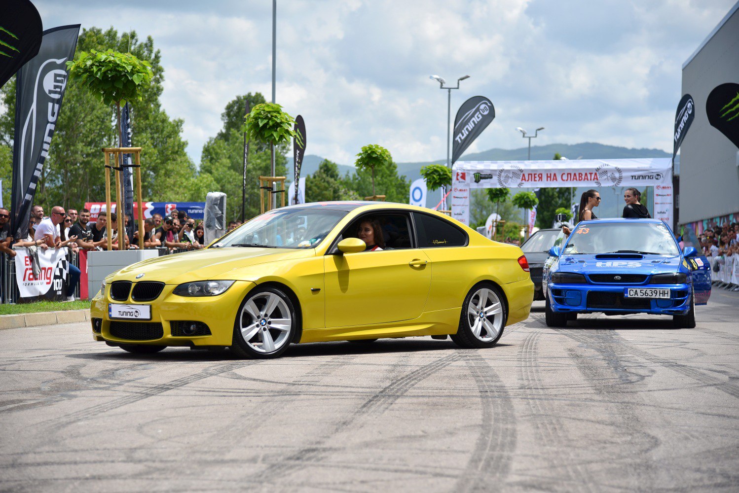 Yellow BMW M3 coupe with blue rally car at tuning event