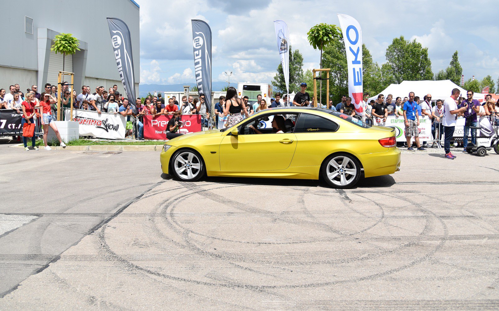 Yellow sports coupe side view with crowd and tire marks