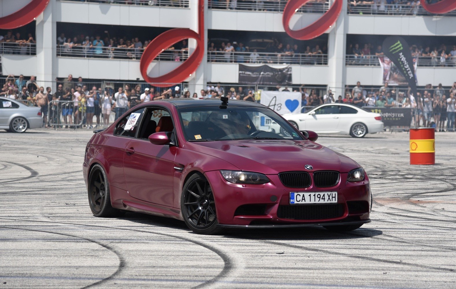 Matte red coupe with black rims performing drift maneuver