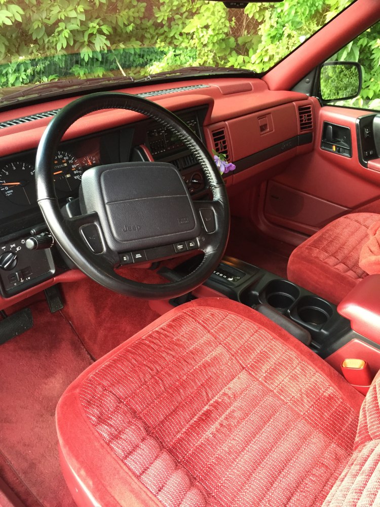 Red interior dashboard and black steering wheel with digital and analog instrument cluster