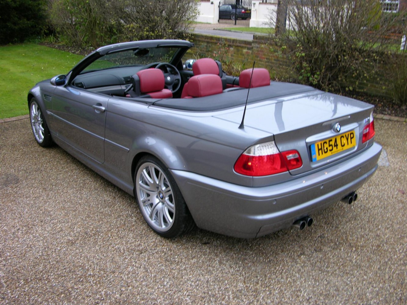 Rear angled view of convertible with dual exhaust and red leather seats