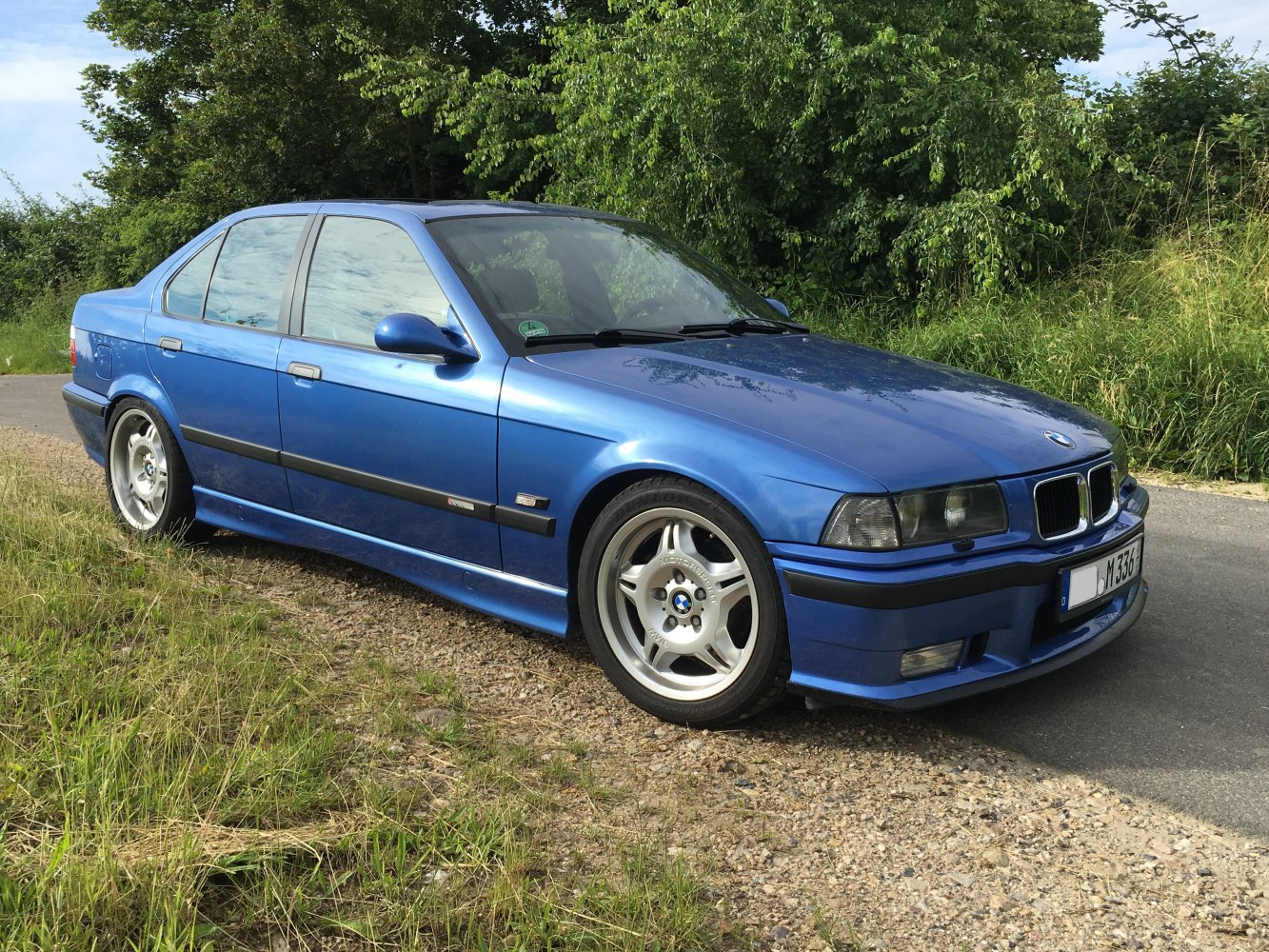 Blue sporty sedan with classic 5-spoke racing wheels and aerodynamic body kit