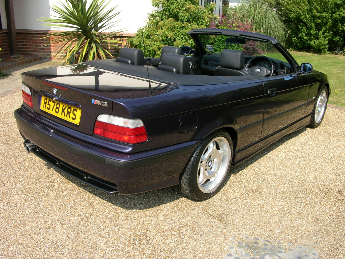 Rear and side view of a classic convertible with soft top down