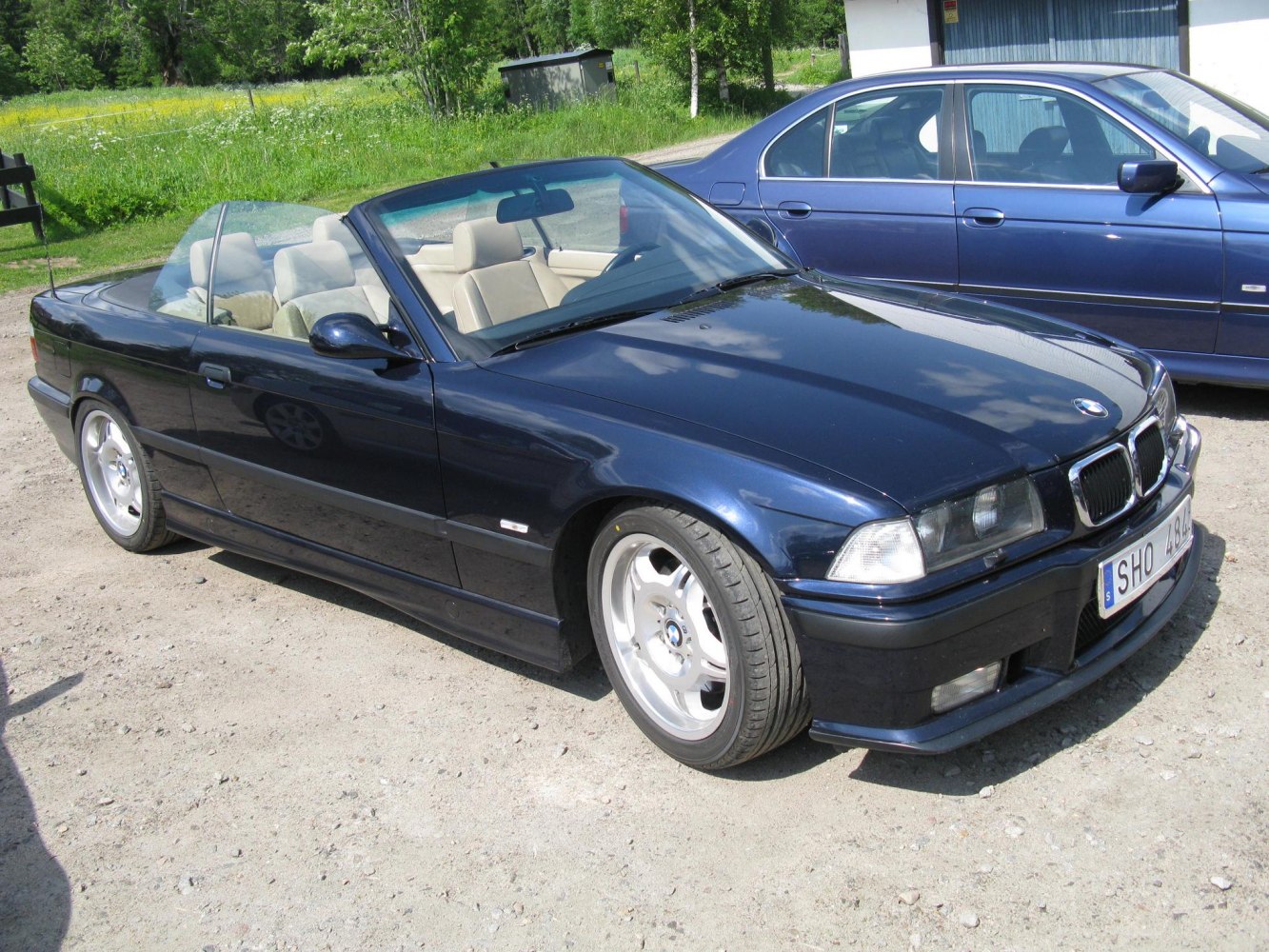 Convertible BMW with open roof and alloy wheels on sunny day