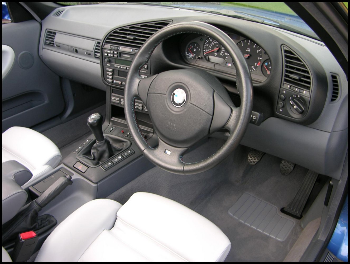 Right-hand drive BMW interior with manual transmission and distinct dashboard.