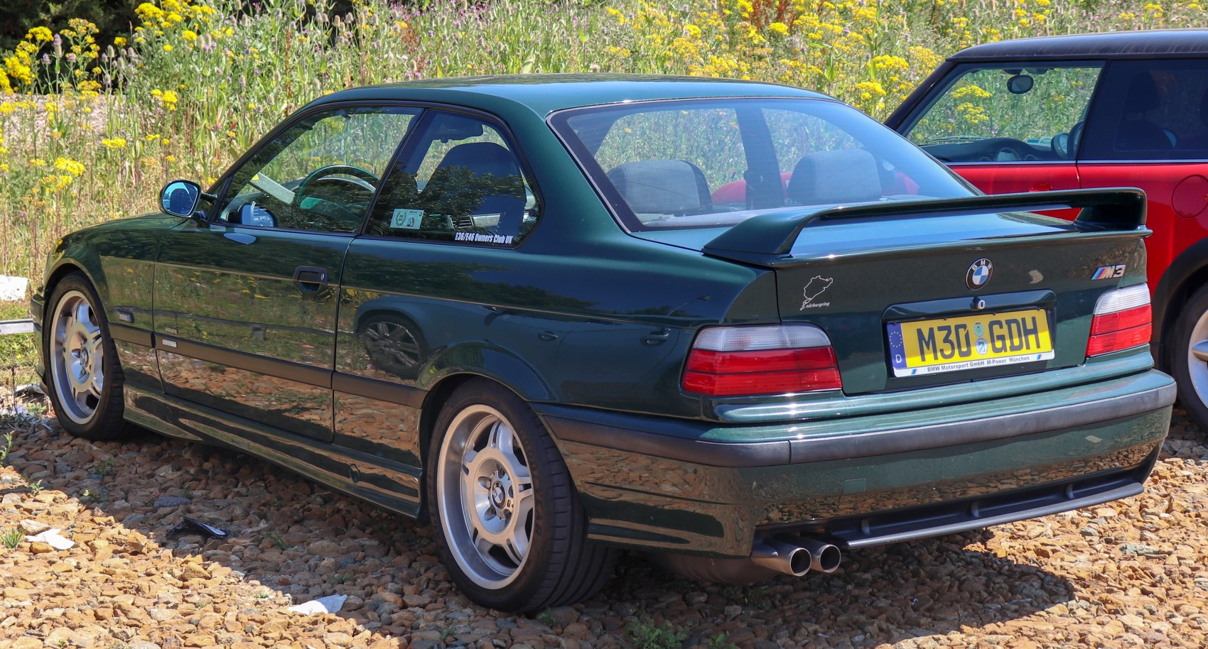 Rear and side view of performance coupe with alloy wheels and spoiler