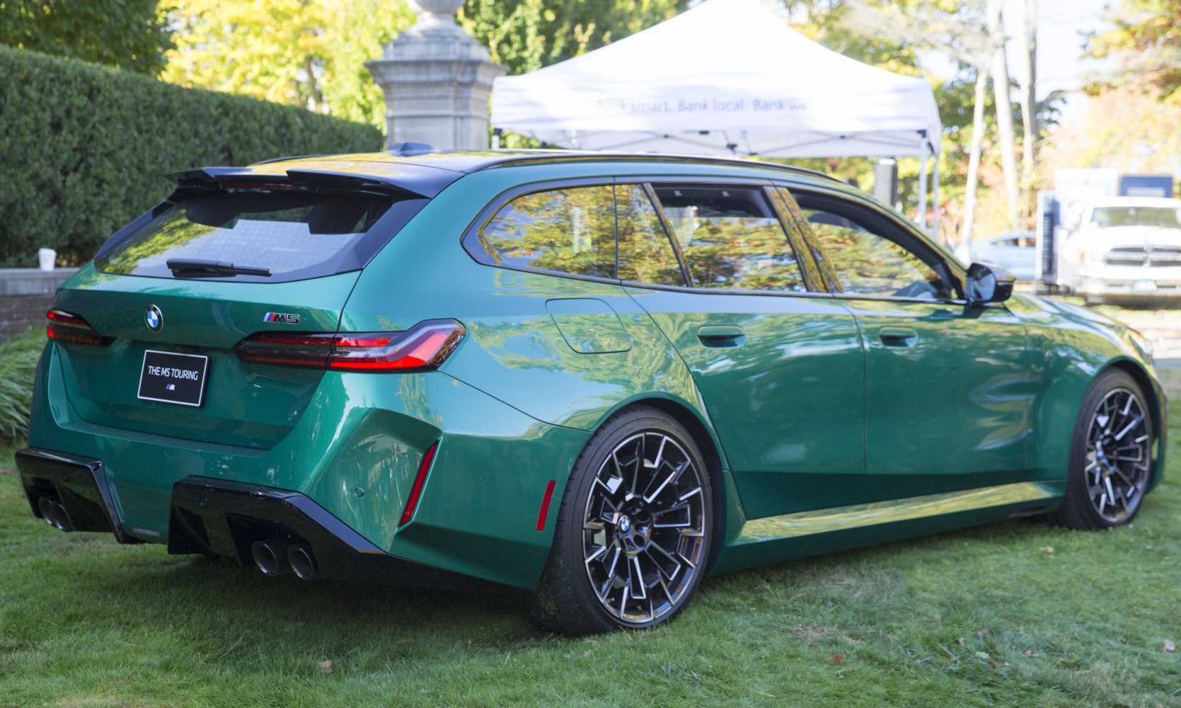 Green BMW M5 Touring rear side view with quad exhausts and sporty wheels