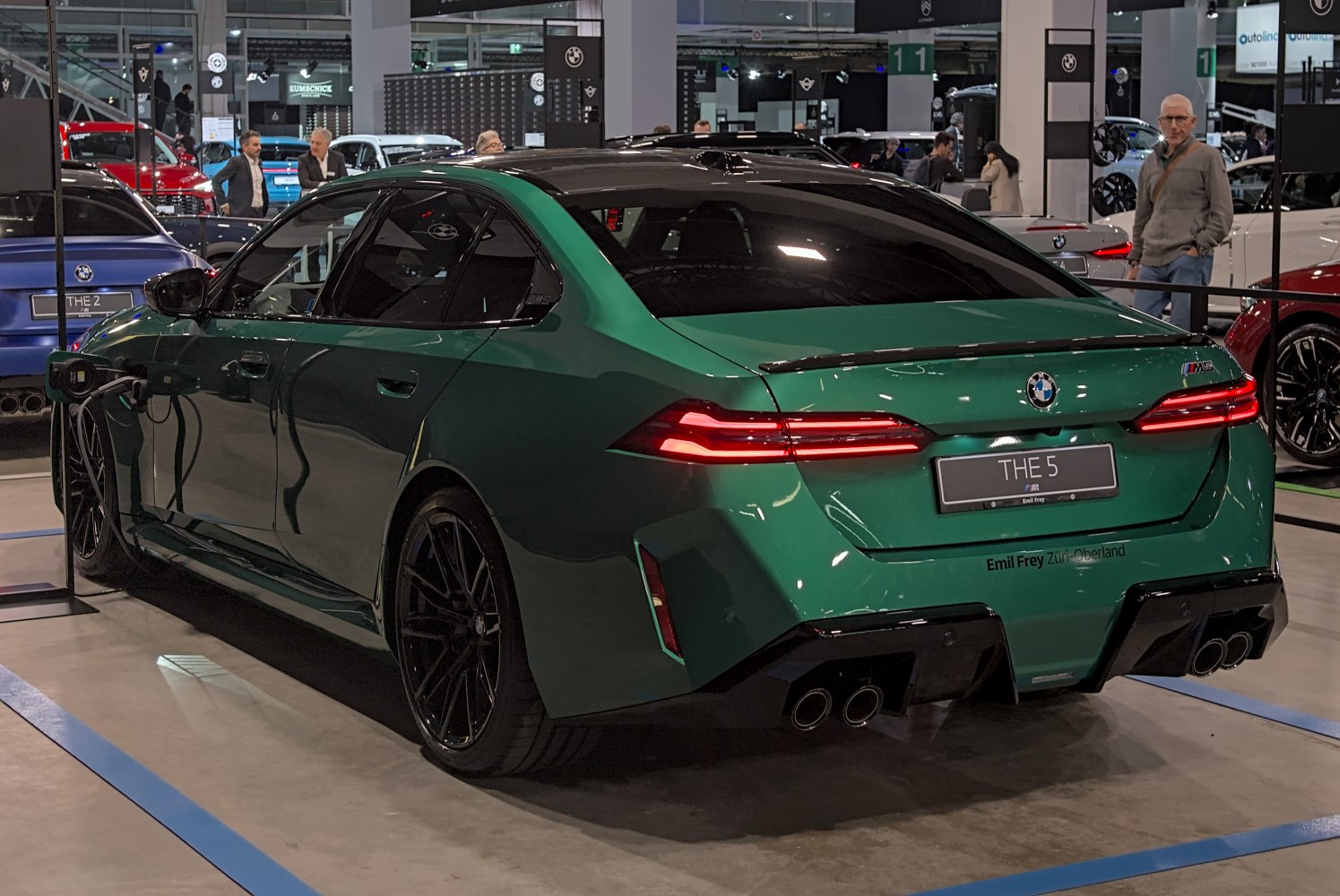 Rear view of green sedan with quad exhausts and electric charging port