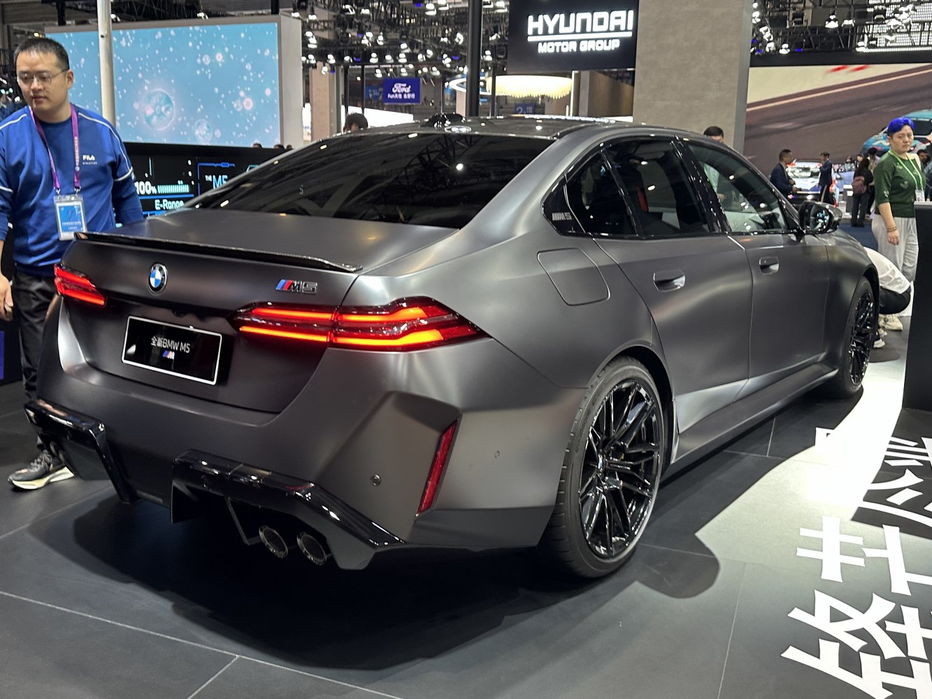 Rear view of matte gray luxury performance sedan with quad exhaust and distinctive taillights.