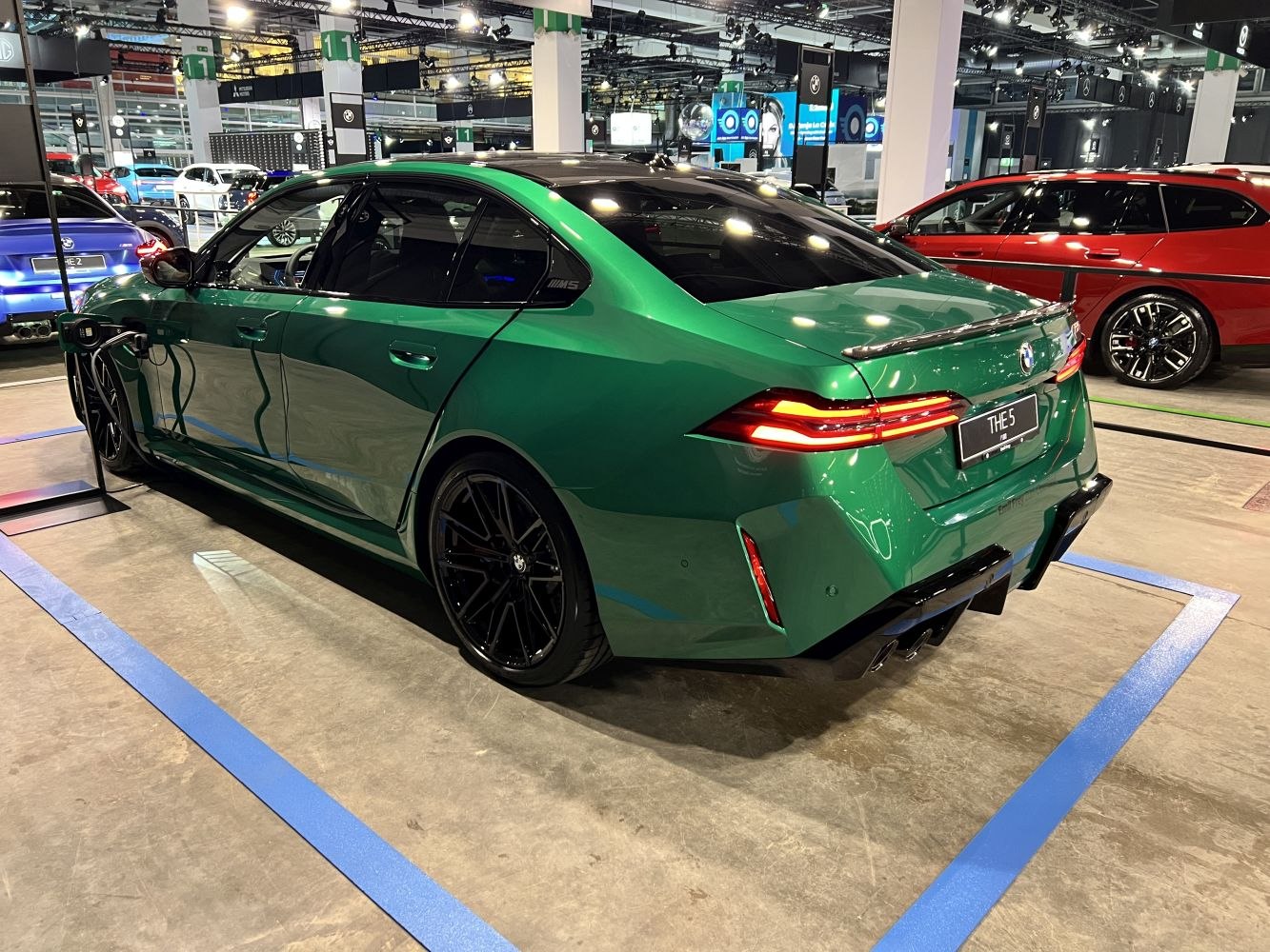 Green luxury sedan rear with distinct taillights and black rims