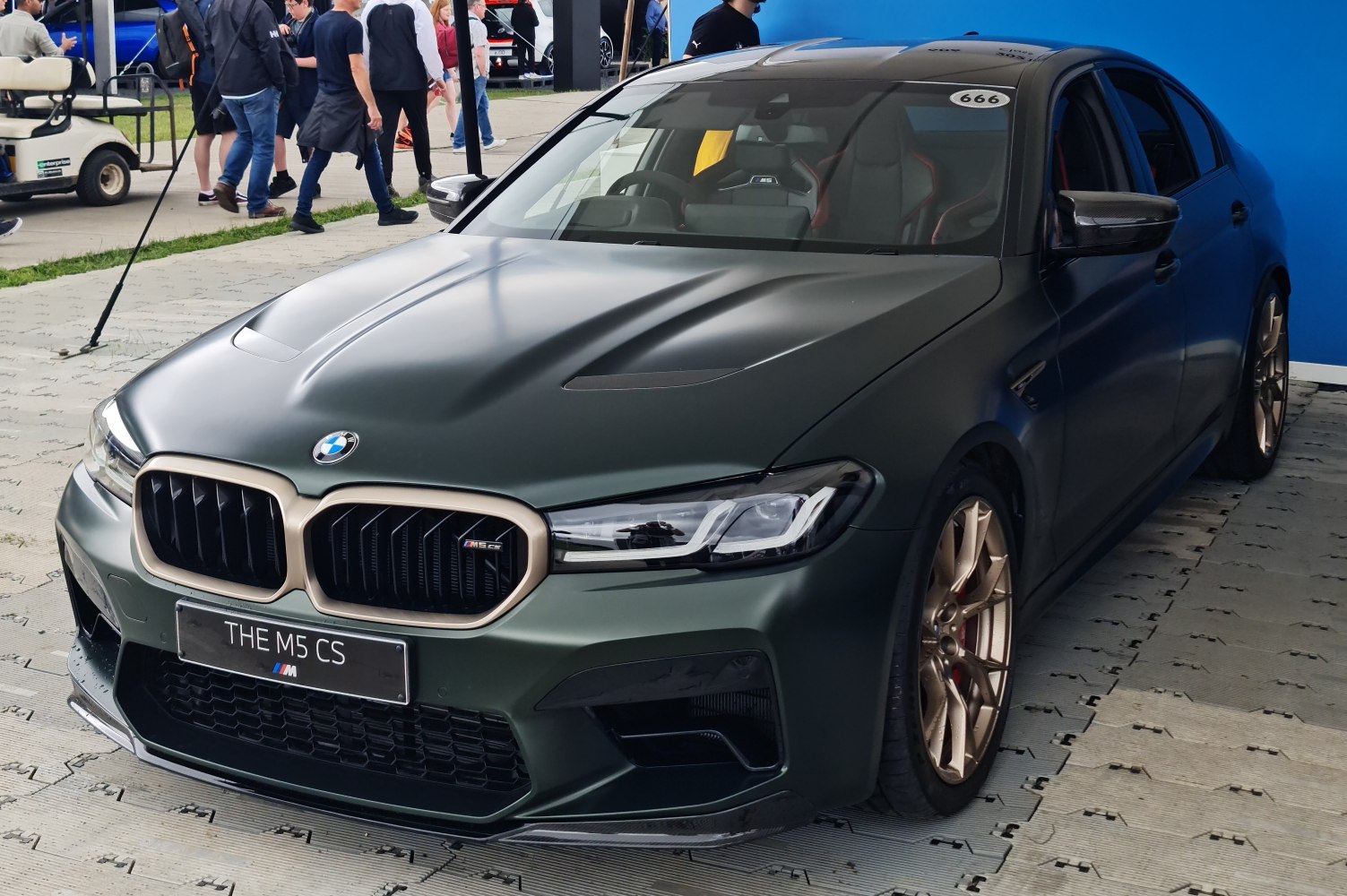Matte green sporty sedan with gold wheels and carbon fiber mirrors