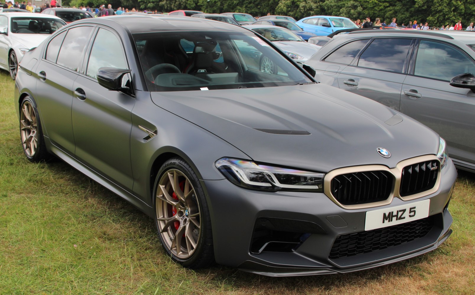 Matt paint BMW sedan with bronze multi-spoke wheels and carbon fiber mirror caps
