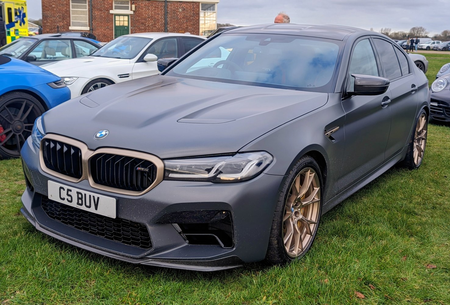 Matte gray performance sedan front with gold alloy wheels