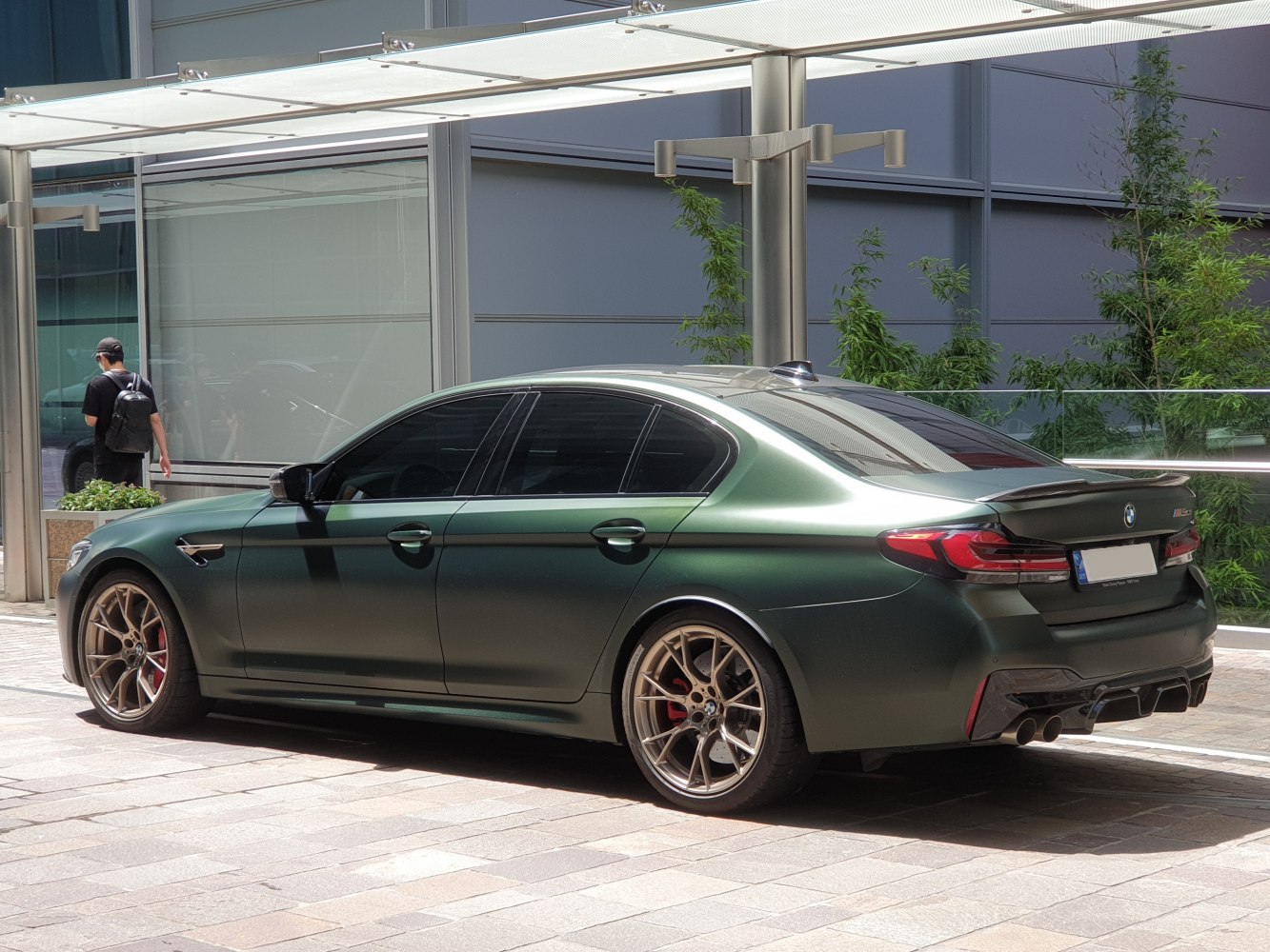 Matte green sporty sedan rear side with alloy wheels and quad exhaust